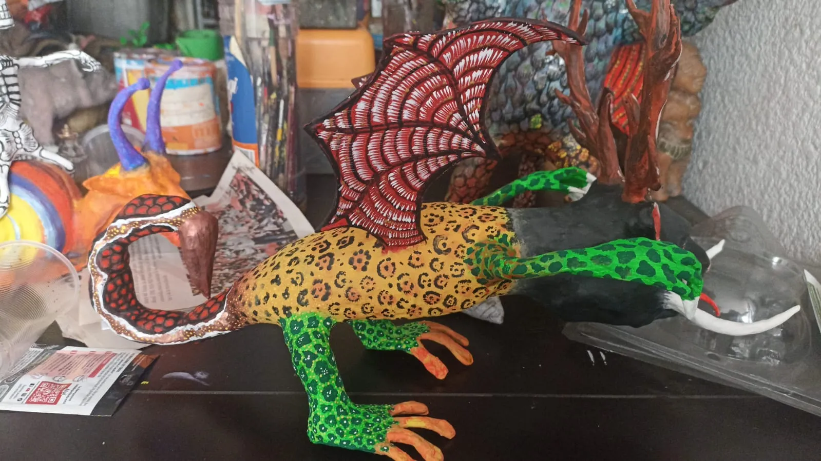 Side view of the antlered jaguar alebrije: coiled tail, wing and green legs.