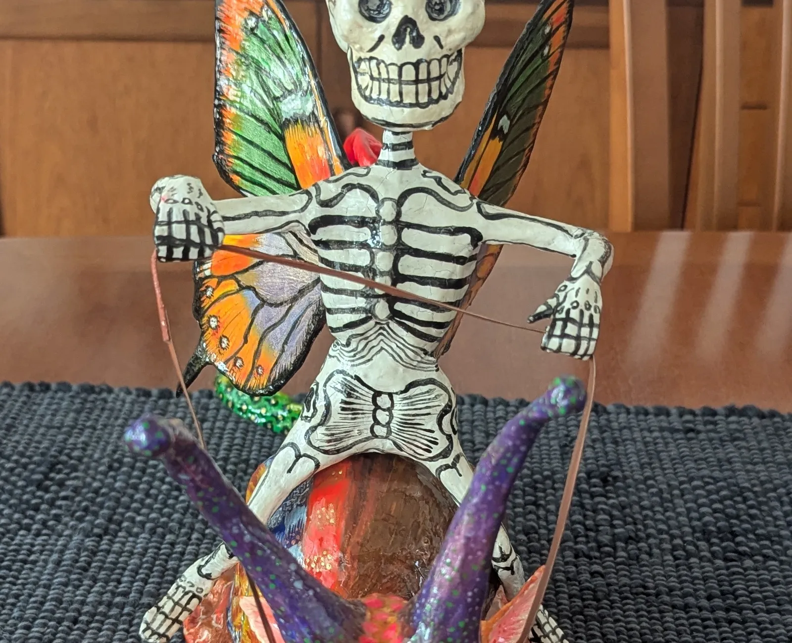 A skull with monarch-butterfly wings in orange, black and violet.
