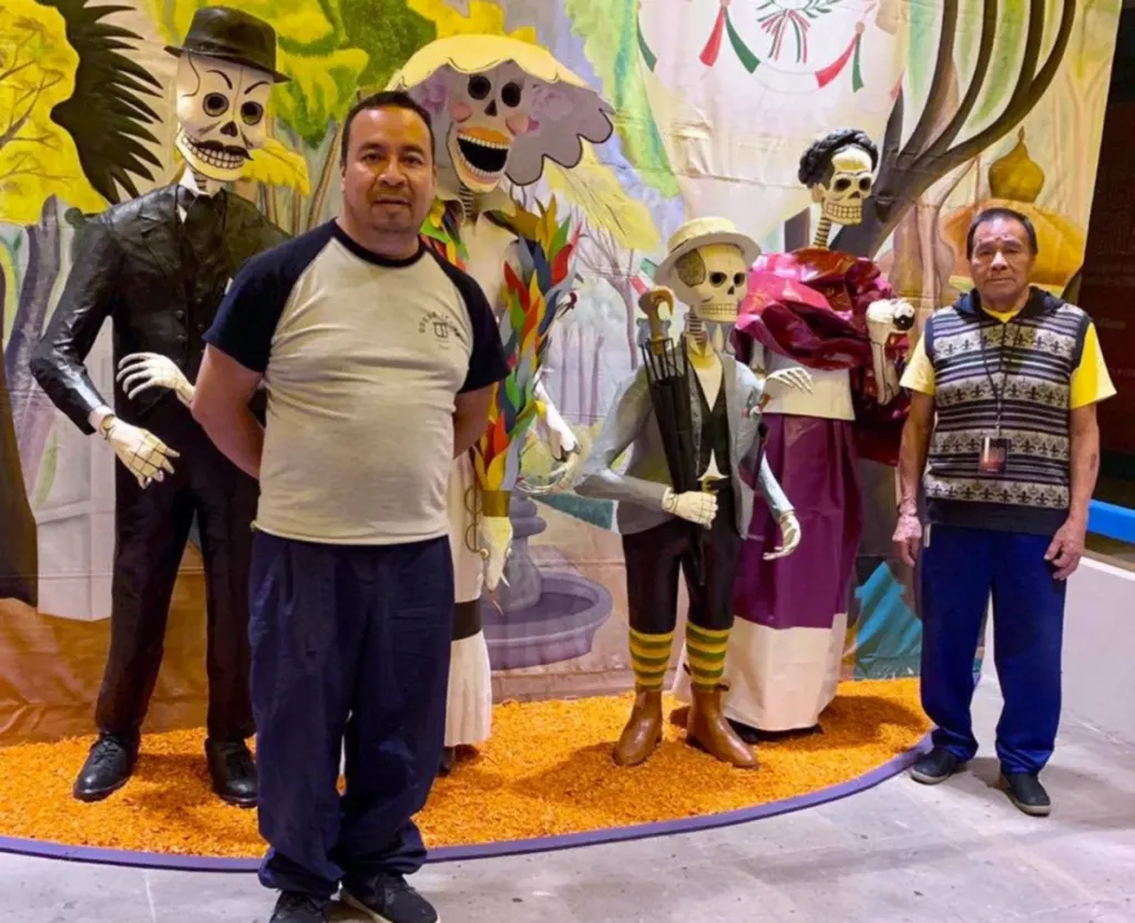 Felipe Linares Vargas and Felipe Linares Mendoza standing before four life-size cartonería skeletons.