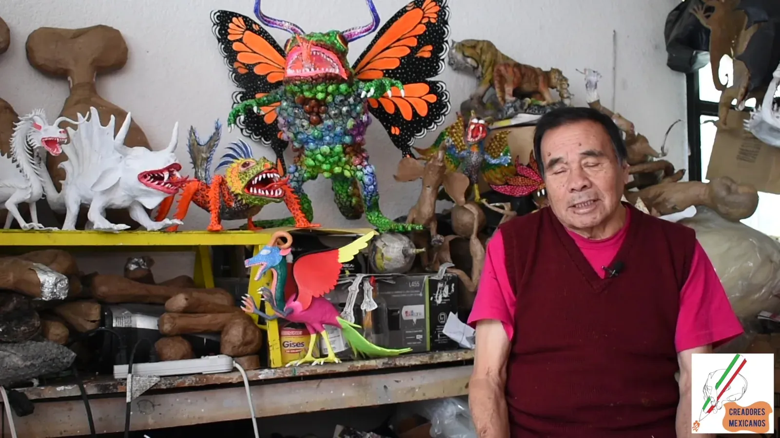 Felipe Linares Mendoza junto a varios alebrijes terminados de colores vivos.