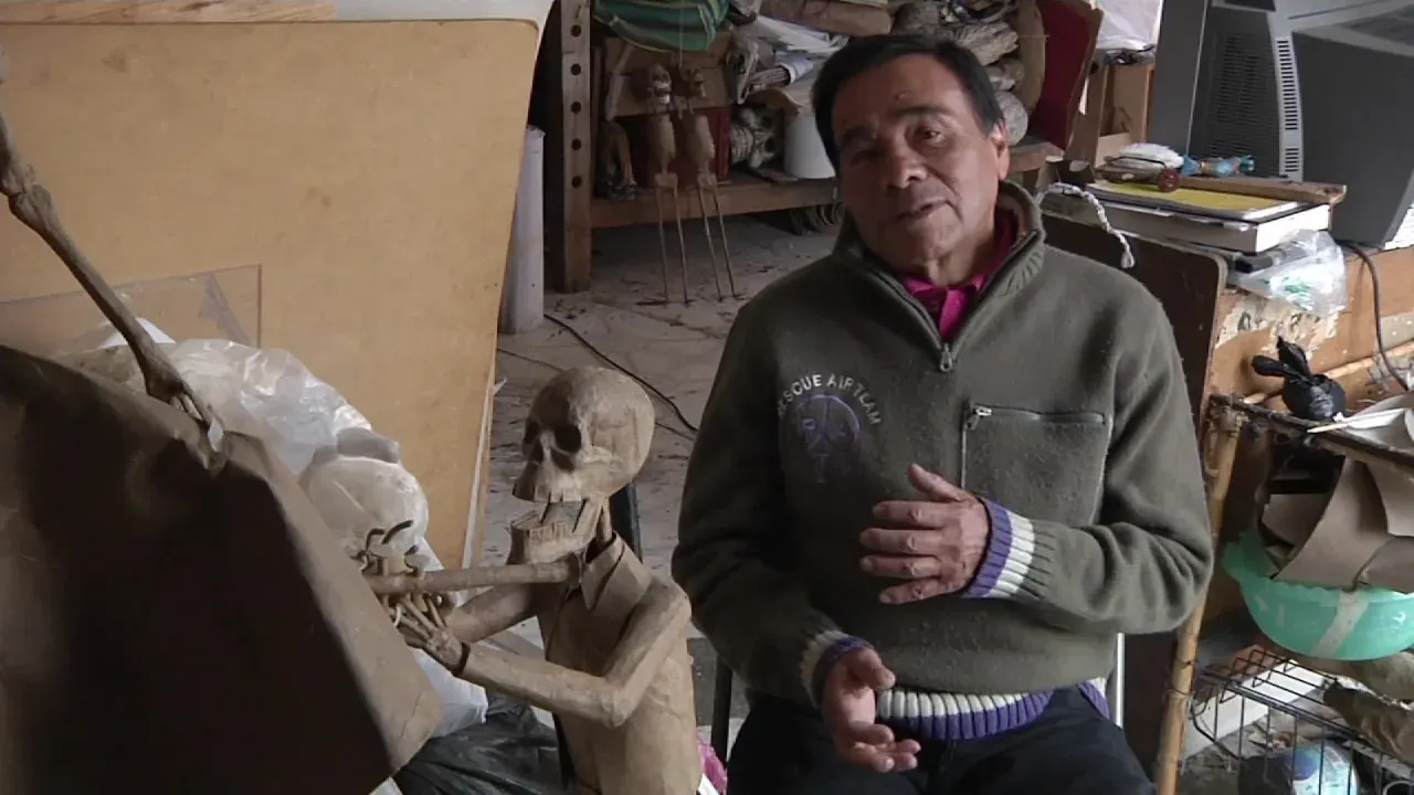 Felipe Linares Mendoza, de frente, con suéter verde, en su taller.