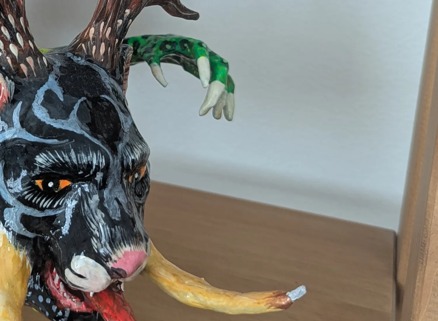 Curved tusks modeled in paper and a long vermilion tongue.