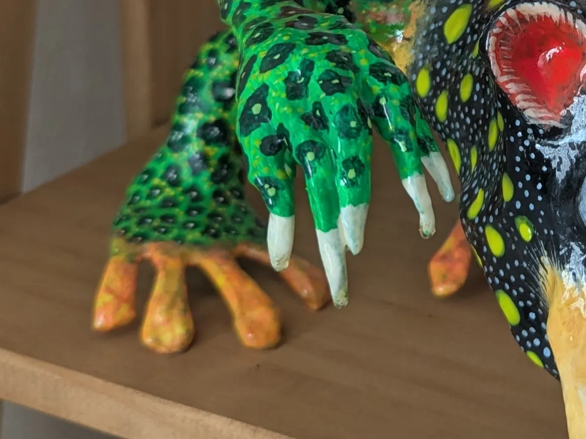 Green claws covered in scales painted one by one; ivory nails.