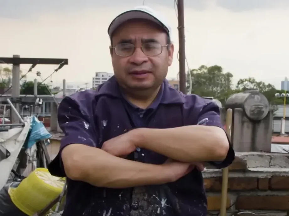 Leonardo Linares Vargas, arms crossed, shirt stained with paint, on the workshop rooftop.