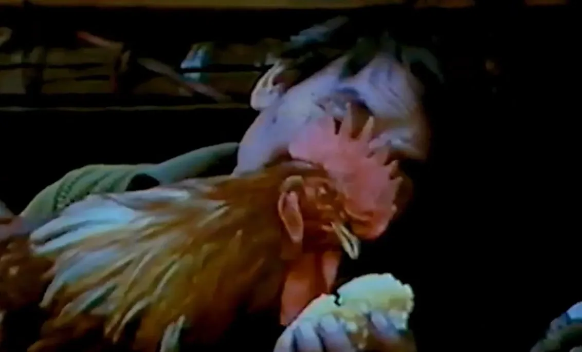 Fotograma de 1975: Pedro Linares López, de perfil, sostiene contra el pecho a Barbas, un gallo rojizo, en un interior en penumbra.