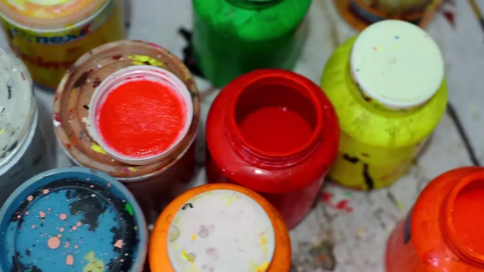 Jars of colored acrylic paint on the table of Leonardo Linares’s workshop.